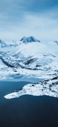 an aerial view of a snow covered landscape with a lake